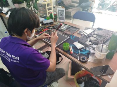 Hình ảnh một kỹ thuật viên đang sửa chữa mainboard laptop với các dụng cụ chuyên nghiệp.
